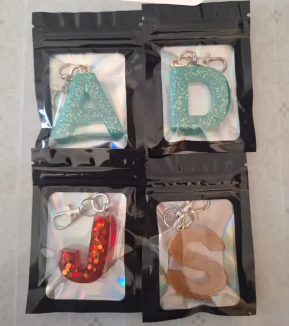 Initial keychains A, D, J and S packed in window pouches